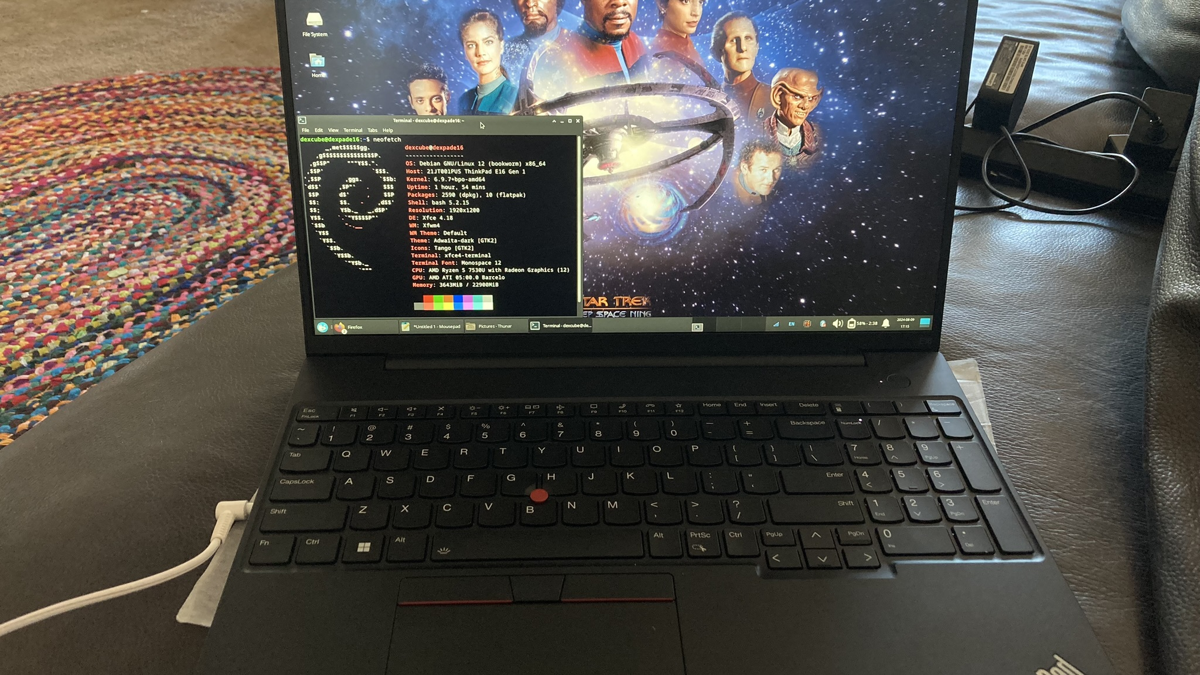 AMD Thinkpad E16 with headphone plugged in. On the screen is Debian 12 Bookworm running on a backports kernel. The desktop background shows characters from the science fiction series Star Trek: Deep SpaceN Nine.